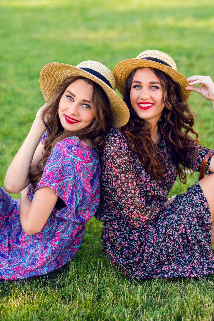 two cheerful twins sitting green meadow enjoy time together